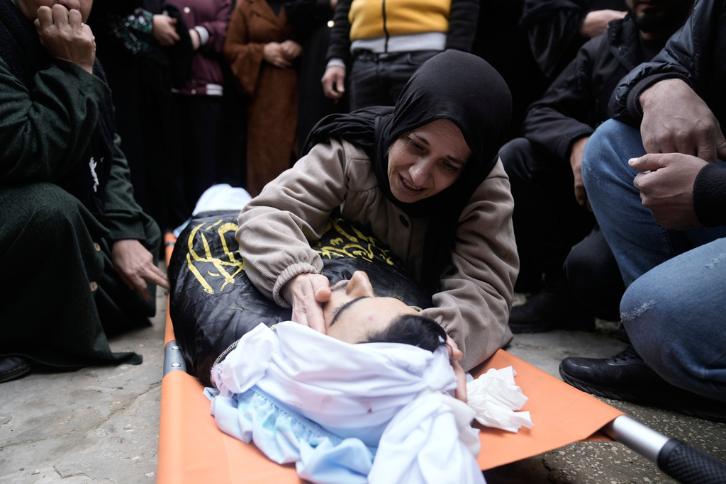 Palestinian mother of Ahmad Ziyoud, draped in the flag of the Islamic Jihad militant group, mourns during his funeral in Silat al-Harithiya, near Jenin, in the West Bank, Sunday, Dec. 21, 2025. (AP Photo/Majdi Mohammad)