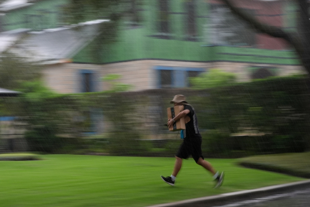 Venezuelan asylum seeker Luis, 30, runs through the rain as he delivers packages in Winter Park, Fla.,Tuesday, Aug. 19, 2025. Luis, who fled Venezuela after being an opposition political activist as a university student, was granted a longterm work permit, allowing him to support himself as an Amazon delivery driver as he goes through the legal asylum process. (AP Photo/Rebecca Blackwell)