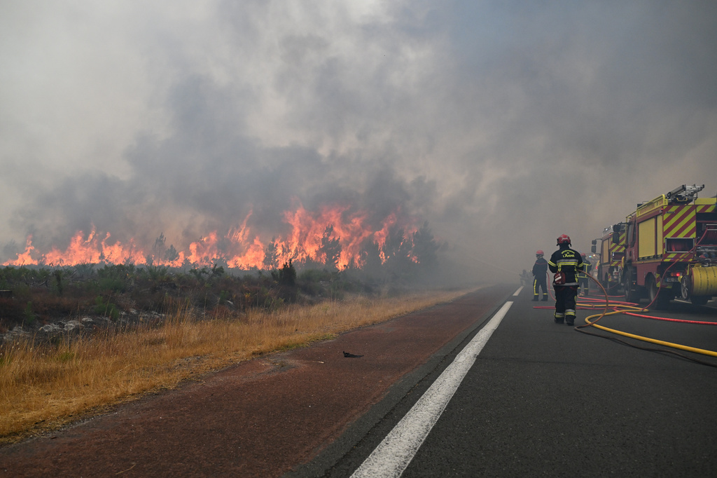 Firefighters spray water in a burning forest near Lacanau, southwestern France, Saturday, July 25, 2026. (AP Photo/Emma Da Silva)