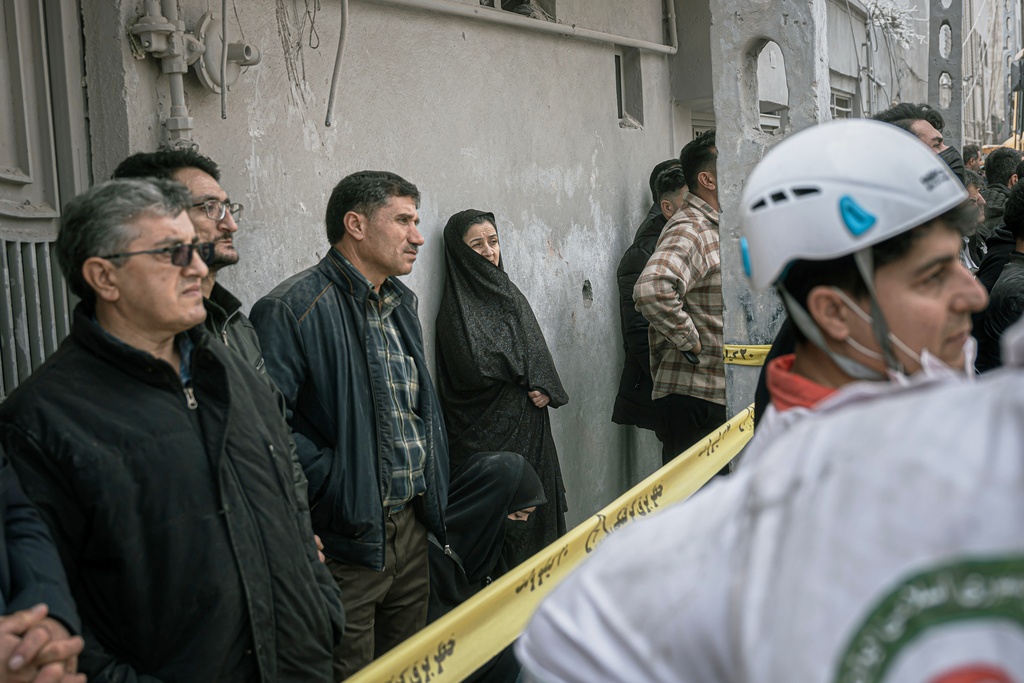 Residents look on as first responders inspect the rubble and search for victims at a residential building hit in an overnight strike during the U.S.-Israeli military campaign in Tabriz, East Azerbaijan Province, northwestern Iran, Tuesday, March 24, 2026. (AP Photo/Matin Hashemi)