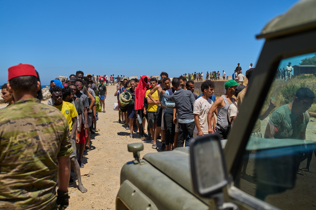 Migrants who crossed into Spain from Morocco line up for water distributed by Spanish soldiers in the Spanish enclave of Ceuta, Sunday, Aug. 2, 2026. (AP Photo/Bernat Armangue)