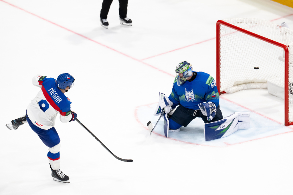 Slovakia's Filip Mesar, left, scores the winning goal past Slovenia's goaltender Lukas Horak during a shootout during the Group B preliminary round game between Italy and Norway at the men's ice hockey world Championship in Fribourg, Switzerland, Tuesday, May 19, 2026. (Anthony Anex/Keystone via AP)