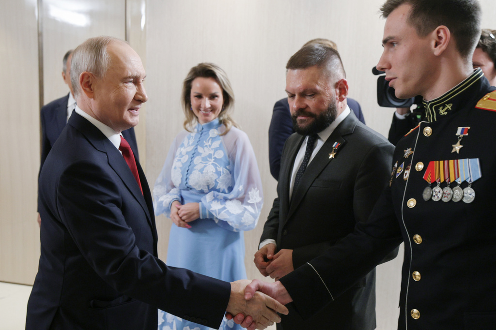 FILE - Russian President Vladimir Putin, left, greets Vladislav Golovin, right, during a meeting with the leaders of the United Russia political party as Presidential Commissioner for Children's Rights Maria Lvova-Belova, center, and military correspondent Yevgeny Poddubny, second right, in Moscow on Saturday, Sept. 5, 2026. (Gavriil Grigorov/Sputnik, Kremlin Pool Photo via AP, File)