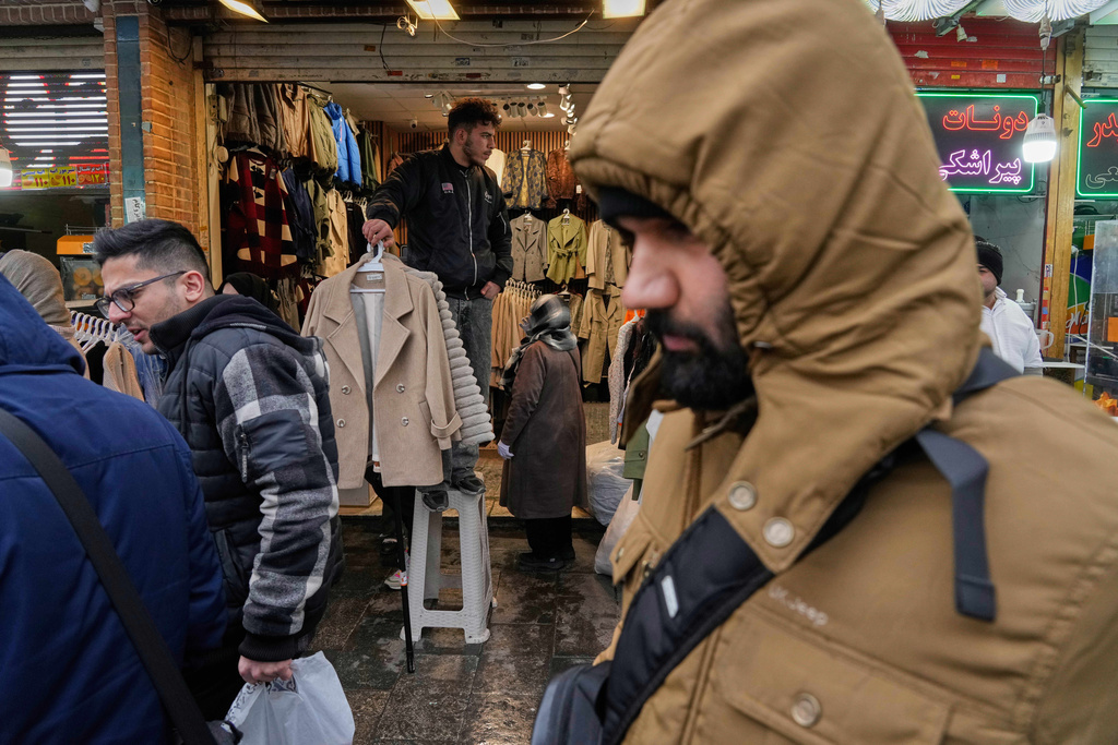 A shopkeeper holds garments at his store at Tehran's historic Grand Bazaar, Tuesday, Jan. 20, 2026, in Iran. (AP Photo/Vahid Salemi)
