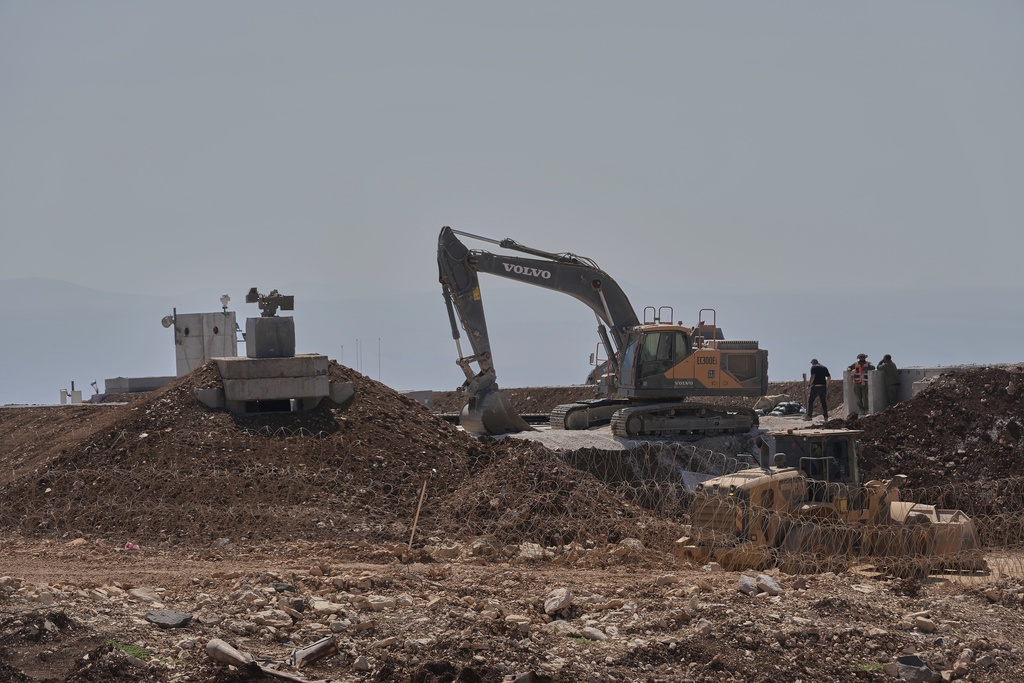 Workers stand beside a bulldozer at one of five new Israeli army positions built inside Lebanese territory along the road between Houla and Kfar Kila following airstrikes and a ground offensive that destroyed nearby villages, southern Lebanon, Wednesday, Aug. 20, 2025.(AP Photo/Hussein Malla)