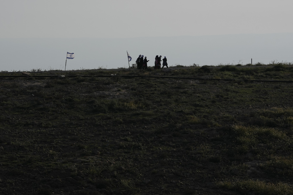 Palestinian students walk to school using an alternative route nearly twice as long because a fence separates their village from the nearby Israeli settlement of Carmel, near the West Bank village of Umm al-Khair, Tuesday, April 14, 2026. (AP Photo/Mahmoud Illean)