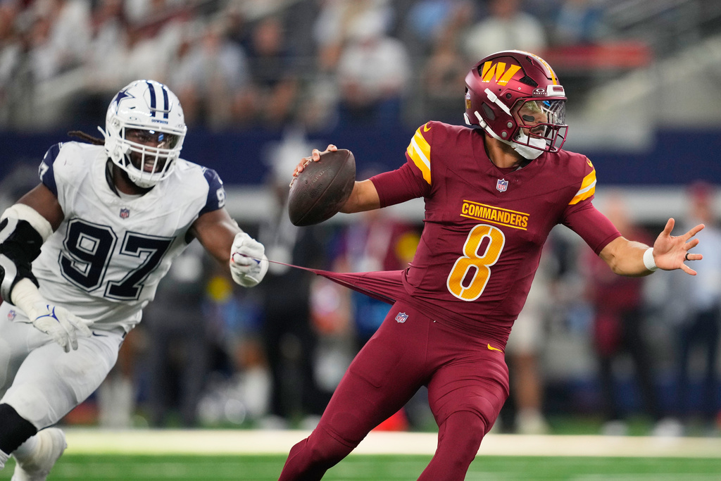 Dallas Cowboys defensive tackle Osa Odighizuwa (97) grabs at the jersey of Washington Commanders quarterback Marcus Mariota (8) during the second half of an NFL football game Sunday, Oct. 19, 2025, in Arlington, Texas. (AP Photo/Tony Gutierrez)