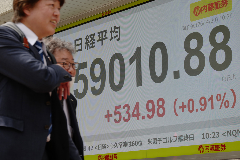 People walk in front of an electronic stock board showing Japan's Nikkei index at a securities firm Monday, April 20, 2026, in Tokyo. (AP Photo/Eugene Hoshiko)