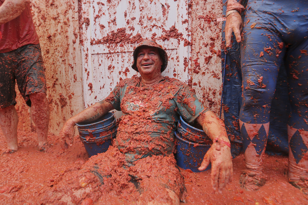 A man sits in a pool of tomatoes during the annual "Tomatina" tomato fight fiesta, in the village of Bunol near Valencia, Spain, Wednesday, Aug. 27, 2025. (AP Photo/Alberto Saiz)