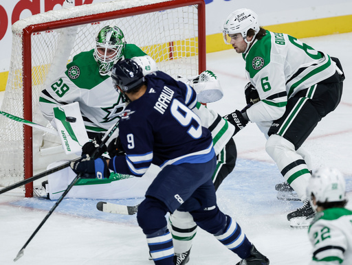 Dallas Stars goaltender Jake Oettinger (29) saves a shot as Winnipeg Jets' Alex Iafallo (9) looks on during first-period NHL hockey game action in Winnipeg, Manitoba, Thursday, Oct. 9, 2025. (John Woods/The Canadian Press via AP) Dallas Stars goaltender Jake Oettinger (29) saves a shot as Winnipeg Jets' Alex Iafallo (9) looks on during first-period NHL hockey game action in Winnipeg, Manitoba, Thursday, Oct. 9, 2025. (John Woods/The Canadian Press via AP)