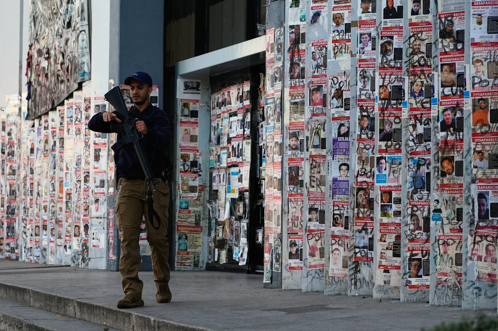 FILE - A police officer walks past posters of missing people in front of the Special Prosecutor's Office for Missing Persons in Guadalajara, Mexico, Feb. 25, 2026. (AP Photo/Marco Ugarte, File)