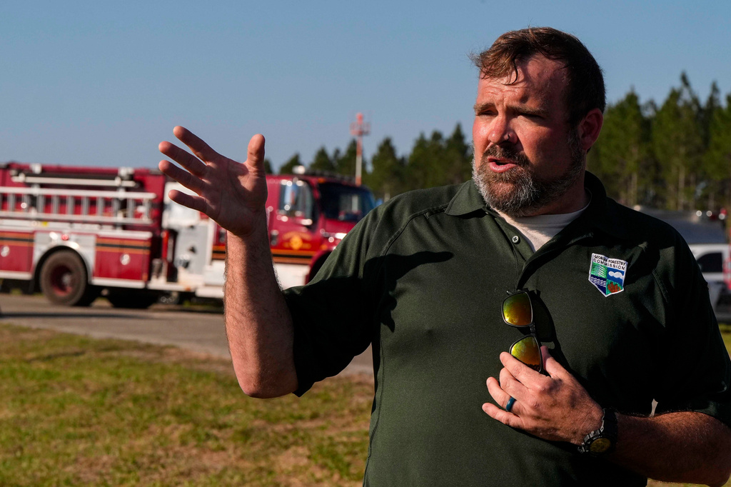 Seth Hawkins with the Georgia Forestry commision speaks to the media as fire crews and truck assemble at the Brantley County Airport as they work the Brantley highway 82 fire, Thursday, April 23, 2026, near Nahunta, Ga. (AP Photo/Mike Stewart)