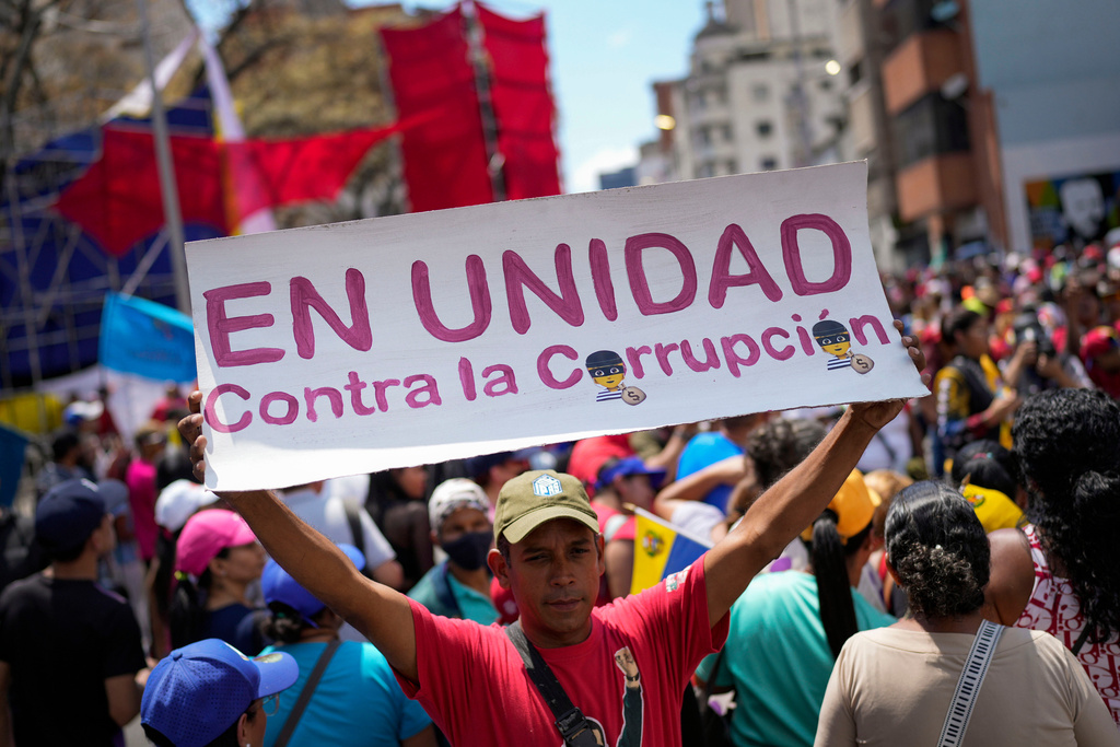 FILE - A government supporter holds a sign with a message that reads in Spanish: "In unity against corruption", during a rally against corruption, in Caracas, Venezuela, Saturday, March 25, 2023. (AP Photo/Matias Delacroix, File)