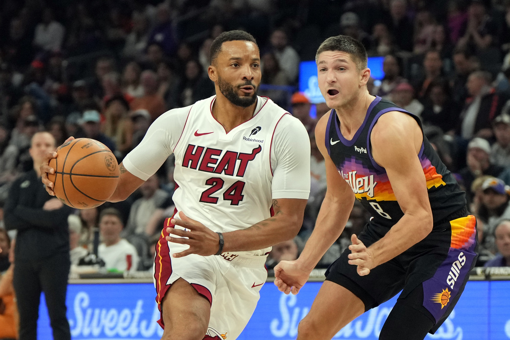Miami Heat guard Norman Powell (24) drives past Phoenix Suns guard Grayson Allen (8) during the first half of an NBA basketball game, Sunday, Jan. 25, 2026, in Phoenix. (AP Photo/Rick Scuteri)