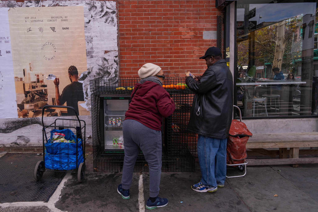 People take food from a One Love Community Fridge, Nov. 15, 2025, in Brooklyn, New York. (AP Photo/Adam Gray)