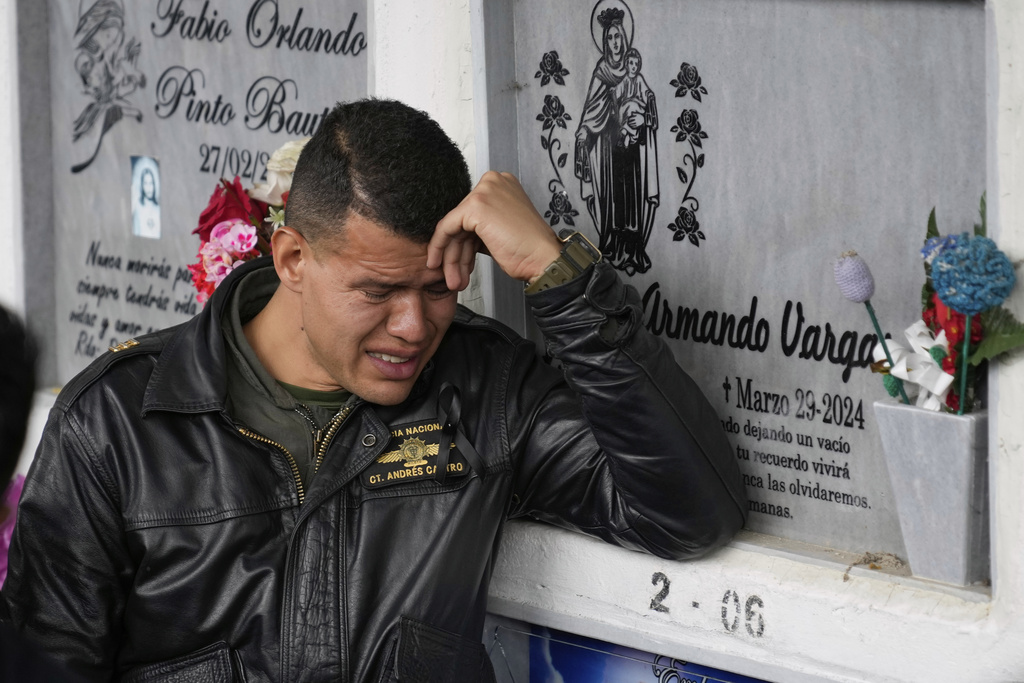 Police Capt. Andrés Castro cries during the funeral of his colleague Capt. Francisco Merchan, a police pilot killed when his helicopter was shot down by a dissident faction of the former FARC guerrilla group, at the cemetery in Mongua, Colombia, Monday, Aug. 25, 2025. (AP Photo/Fernando Vergara)