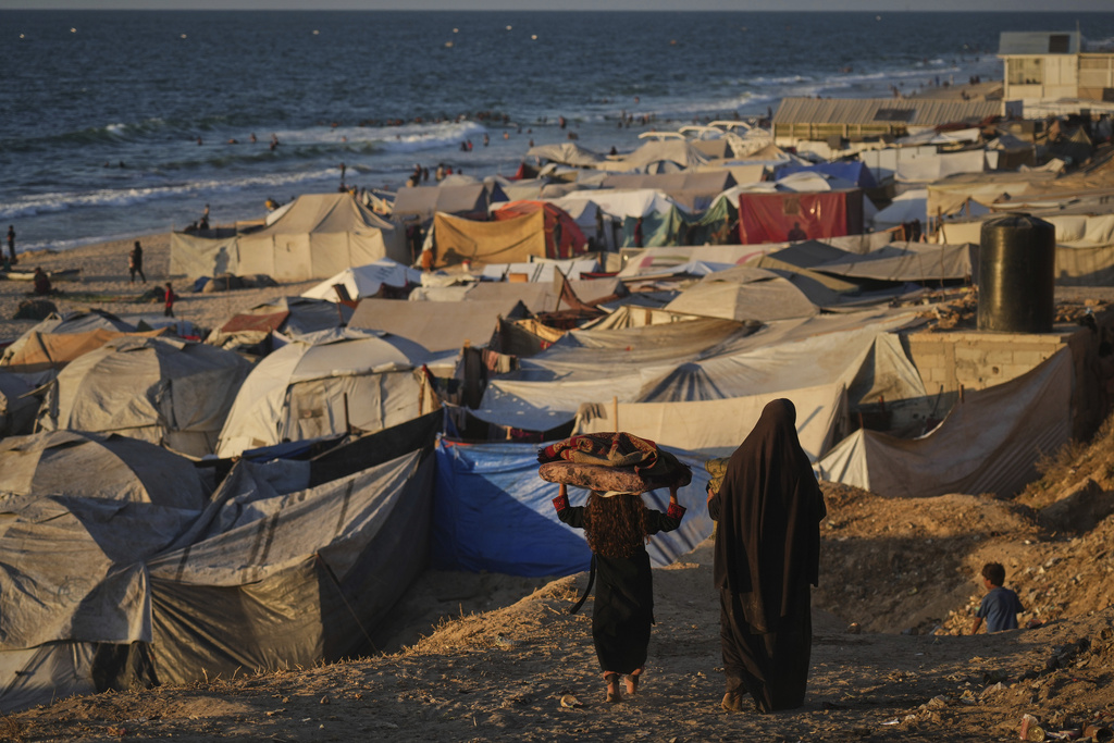 Displaced Palestinians walk through a makeshift tent camp along the shore of Deir al-Balah in the Gaza Strip Tuesday, Sept. 16, 2025. (AP Photo/Jehad Alshrafi)