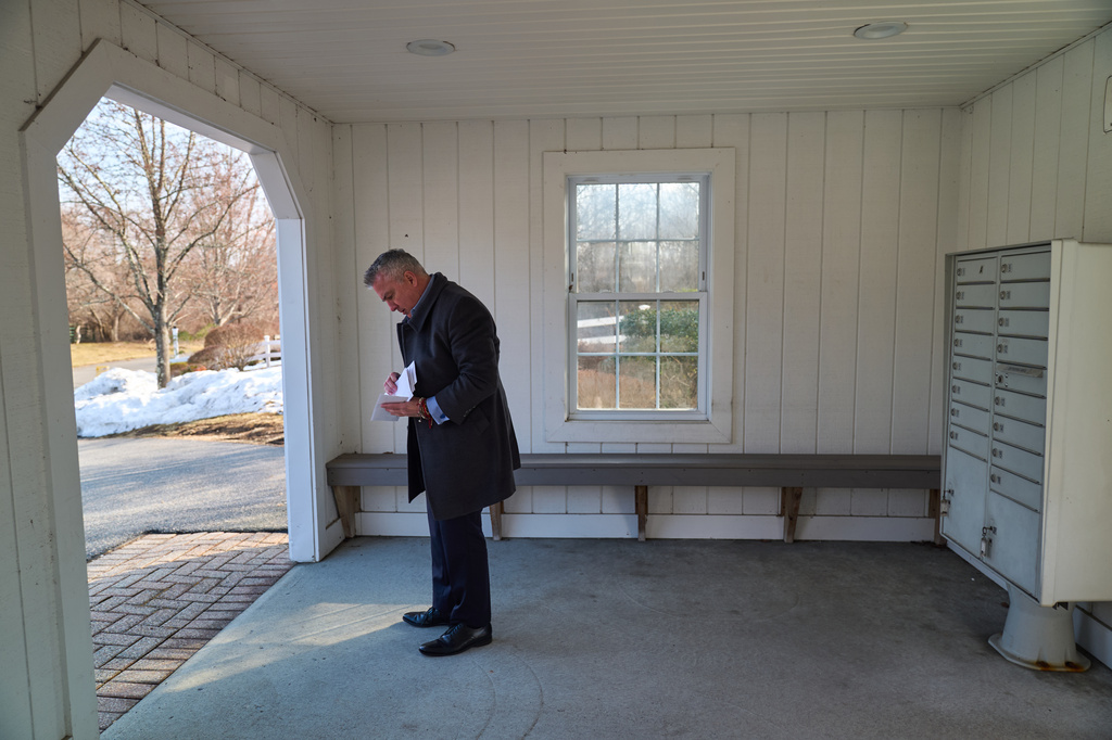Chris Colocousis, whose retirement savings were stolen by a scammer, checks his mail before heading to a work appointment in Raynham, Mass., Tuesday, March 10, 2026. (AP Photo/David Goldman)