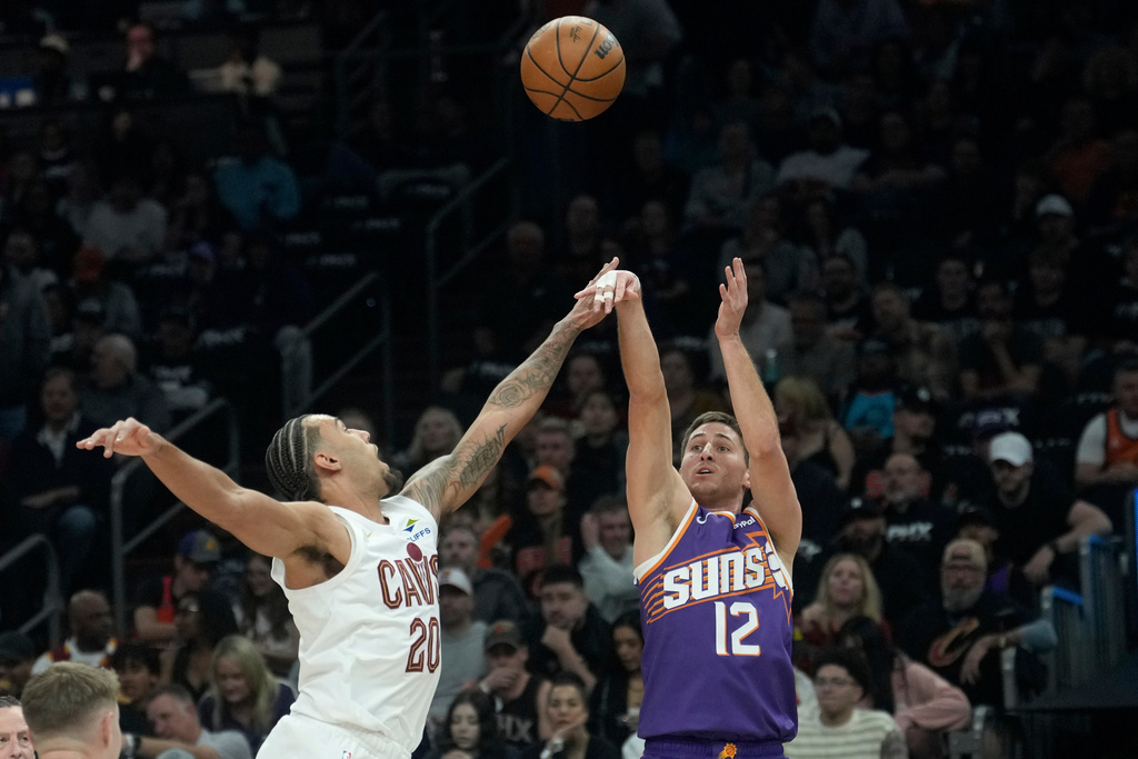 Phoenix Suns guard Collin Gillespie (12) shoots over Cleveland Cavaliers guard Jaylon Tyson (20) during the first half of an NBA basketball game Friday, Jan. 30, 2026, in Phoenix. (AP Photo/Ross D. Franklin)