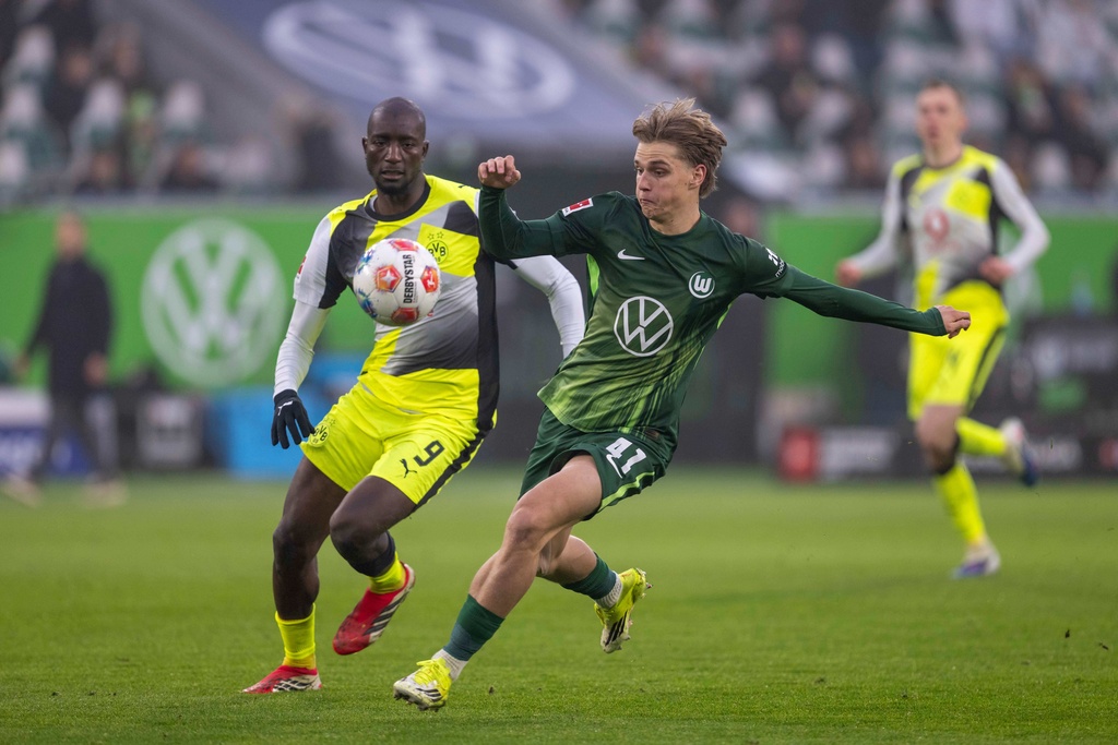 Dortmund's Serhou Guirassy, left, and Wolfsburg's Jan Buerger fight for the ball during their German Bundesliga soccer match in Wolfsburg, Germany, Saturday, Feb. 7, 2026. (David Inderlied/dpa via AP)