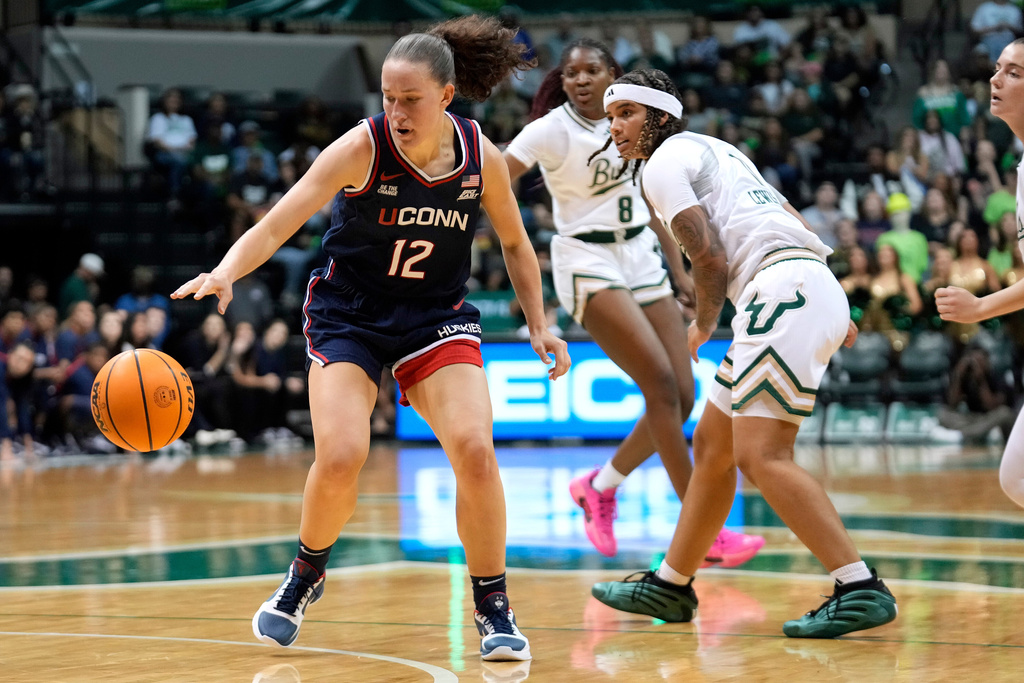 UConn guard Ashlynn Shade (12) steals the ball from South Florida guard Kirsten Lewis-Williams (11) during the second quarter of an NCAA college basketball game Tuesday, Dec. 2, 2025, in Tampa, Fla. (AP Photo/Chris O'Meara)