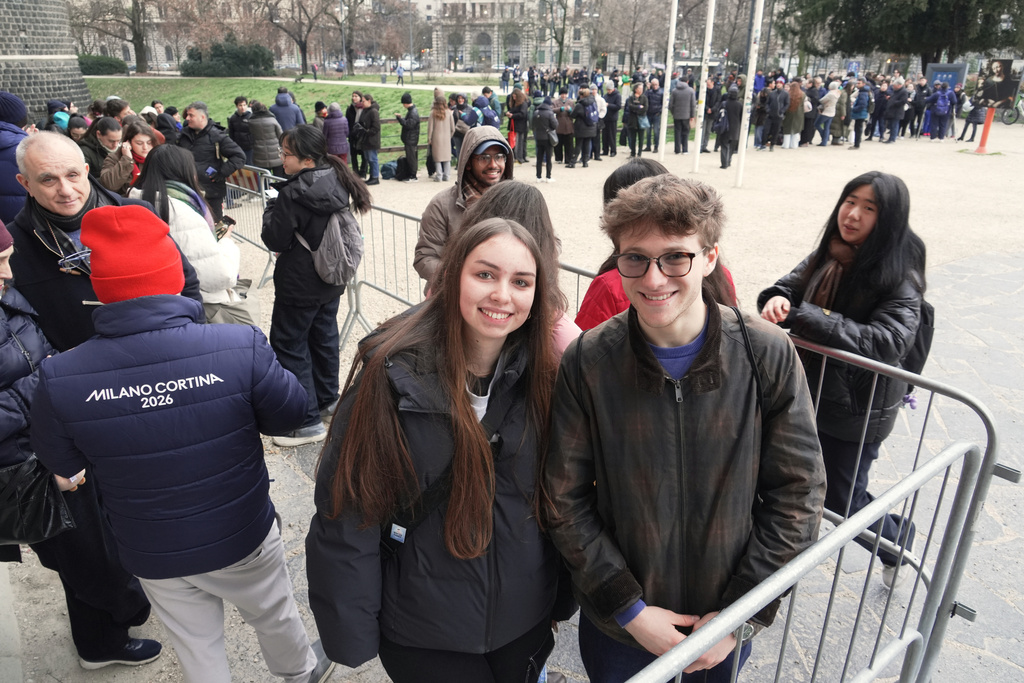 Beatrice Biondi and Pietro Sartena queue up at Milan's Sforza Castle to pick up the coveted pin of the day featuring the landmark by the YesMilano city promoters, at the 2026 Winter Olympics, in Milan, Italy, Wednesday, Feb. 11, 2026. (AP Photo/Mustakim Hasnath)