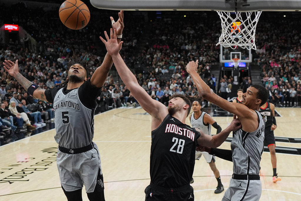 Houston Rockets center Alperen Sengun (28) drives to the basket against San Antonio Spurs guard Stephon Castle (5) and forward Victor Wembanyama (1) during the second half of an NBA basketball game in San Antonio, Sunday, March 8, 2026. (AP Photo/Eric Gay)
