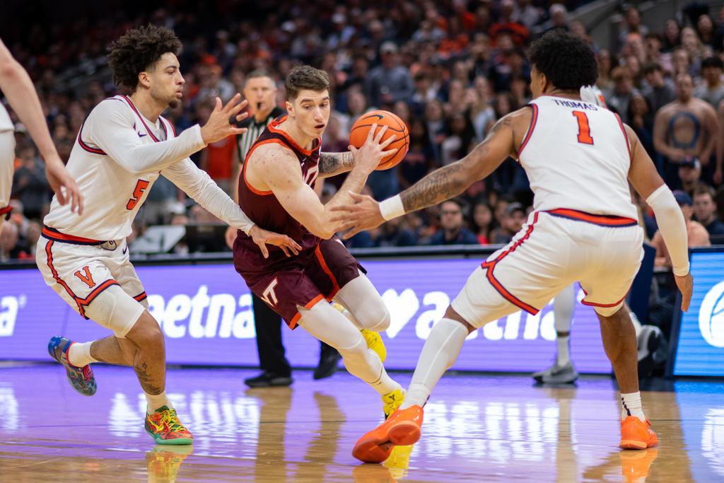 Virginia Tech guard Neoklis Avdalas (17) drives between Virginia guards Malik Thomas (1) and Sam Lewis (5) during the first half of an NCAA college basketball game, Saturday, March 7, 2026, in Charlottesville, Va. (AP Photo/Robert Simmons)