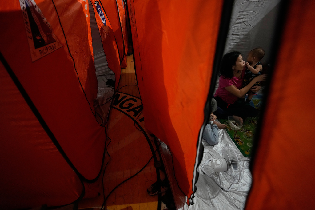 A woman and her family stay inside a tent at an evacuation center as Typhoon Fung-wong enters the country on Sunday, Nov. 9, 2025 in Quezon city, Philippines. (AP Photo/Aaron Favila)