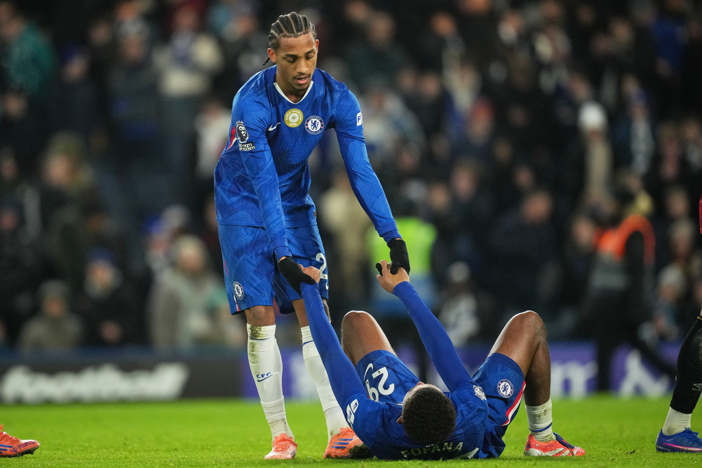 Chelsea's Joao Pedro, top, helps Wesley Fofana stand up after the English Premier League soccer match between Chelsea and Bournemouth in London, England, Tuesday, Dec. 30, 2025. (AP Photo/Kin Cheung)