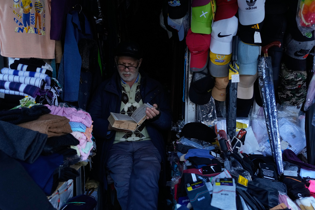 Ghesmat Masoumi reads the Quran at his shop in the port city of Bandar Anzali, Iran, Sunday, Dec. 21, 2025. (AP Photo/Vahid Salemi)