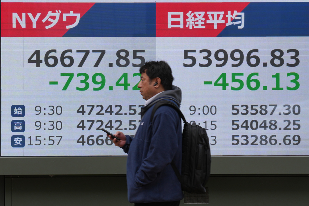 A person walks in front of an electronic stock board showing Japan's Nikkei index at a securities firm Friday, March 13, 2026, in Tokyo. (AP Photo/Eugene Hoshiko)