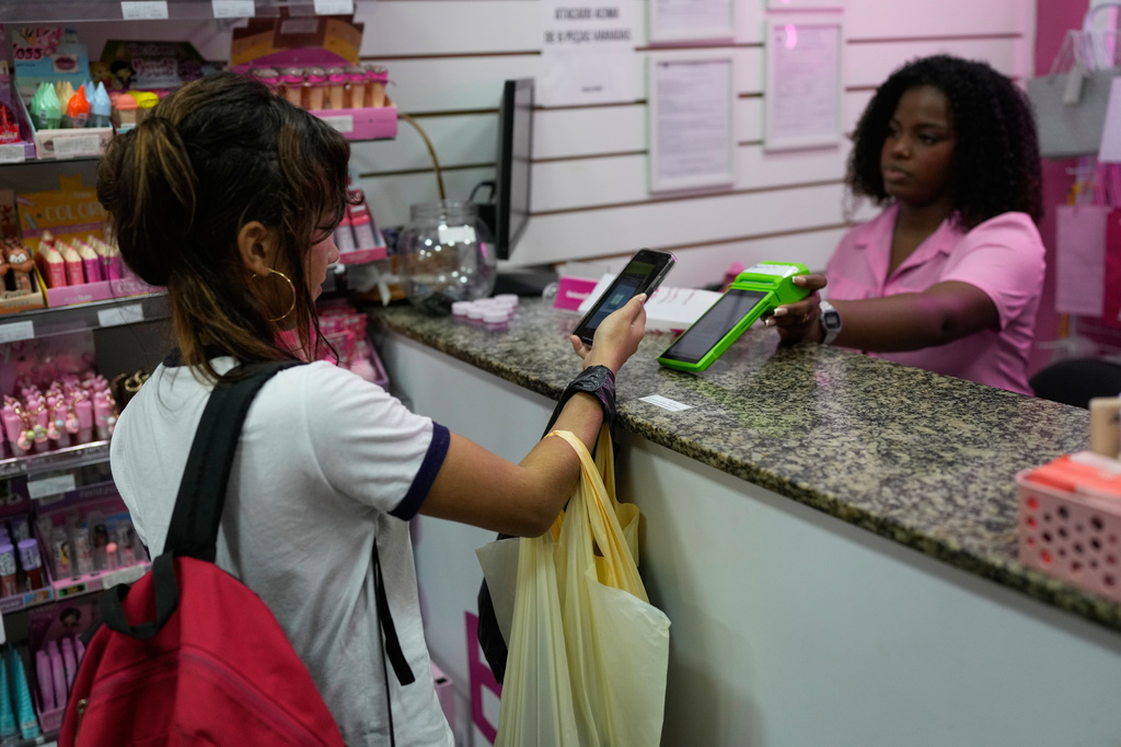 A woman pays using Pix, a free payment system, at a store in Rio de Janeiro, Thursday, April 16, 2026. (AP Photo/Silvia Izquierdo)