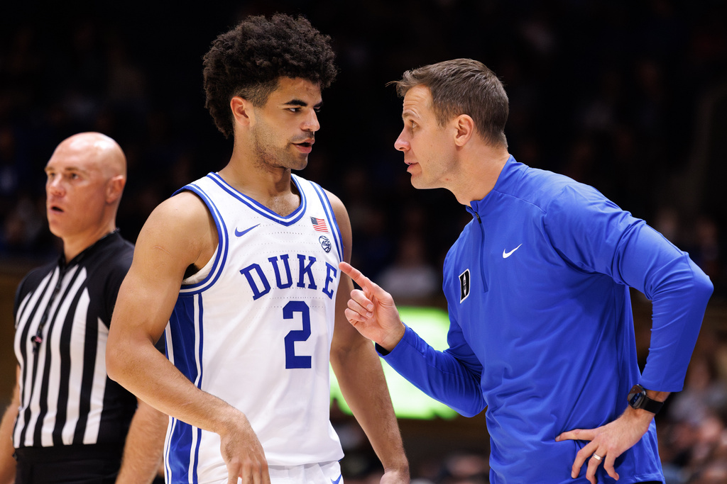 Duke head coach Jon Scheyer, right, speaks to Cayden Boozer (2) during the second half of an NCAA college basketball game against Central Florida in Durham, N.C., Tuesday, Oct. 21, 2025. (AP Photo/Ben McKeown)
