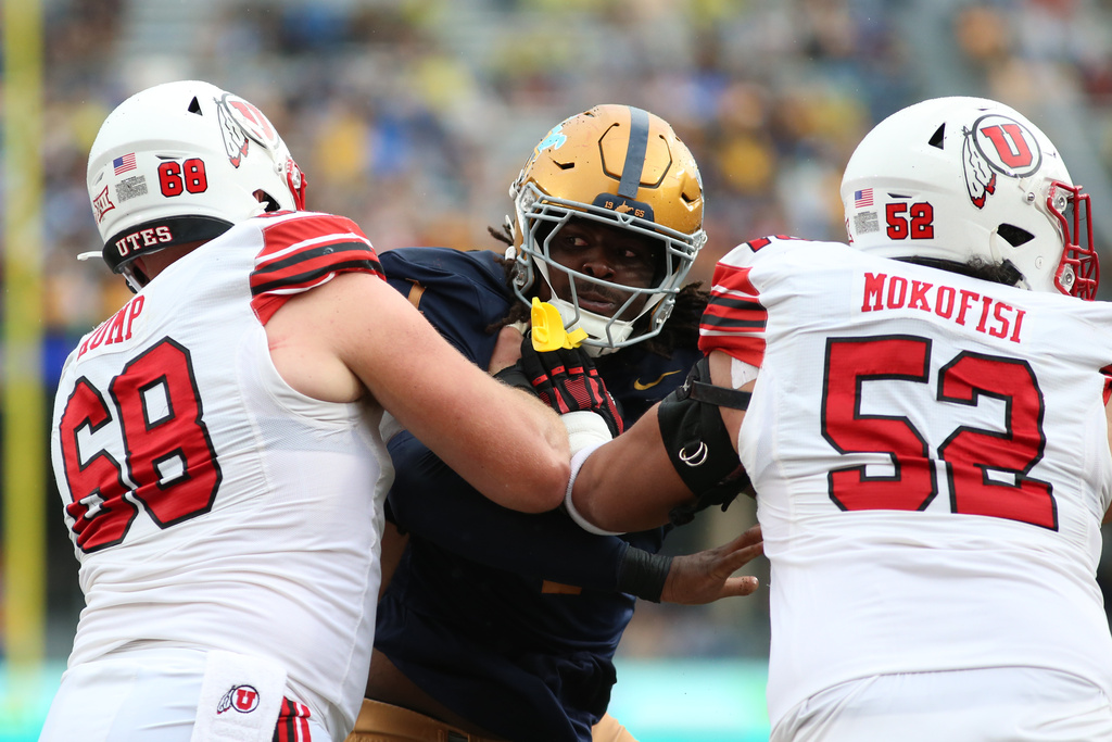 Utah Utes offensive lineman Jaren Kump (68) and Utah Utes offensive lineman Michael Mokofisi (52) block West Virginia Mountaineers defensive lineman Eddie Kelly Jr. (1) during the first half of an NCAA college football game, Saturday, Sept, 27, 2025, in Morgantown, W.Va. (AP Photo/ William Wotring)