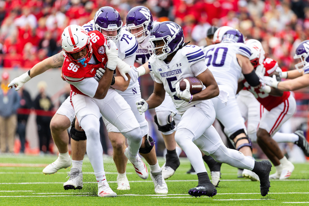 Northwestern running back Caleb Komolafe (5) carries the ball ahead of Nebraska defensive lineman Williams Nwaneri (96) during the first half of an NCAA college football game, Saturday, Oct. 25, 2025, in Lincoln, Neb. (AP Photo/Bonnie Ryan)