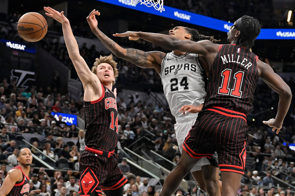 San Antonio Spurs guard Devin Vassell (24) tangles with Chicago Bulls players Leonard Miller (11) and Matas Buzelis (14) during the first half of an NBA basketball game, Monday, March 30, 2026, in San Antonio. (AP Photo/Darren Abate)
