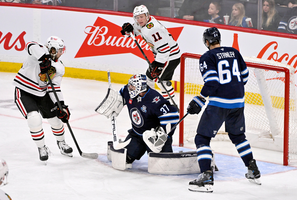 A shot deflected by Chicago Blackhawks' Landon Slaggert (left) goes over Winnipeg Jets goaltender Connor Hellebuyck (37) during the third period of their NHL hockey game in Winnipeg, Tuesday March 3, 2026. (Fred Greenslade/The Canadian Press via AP)