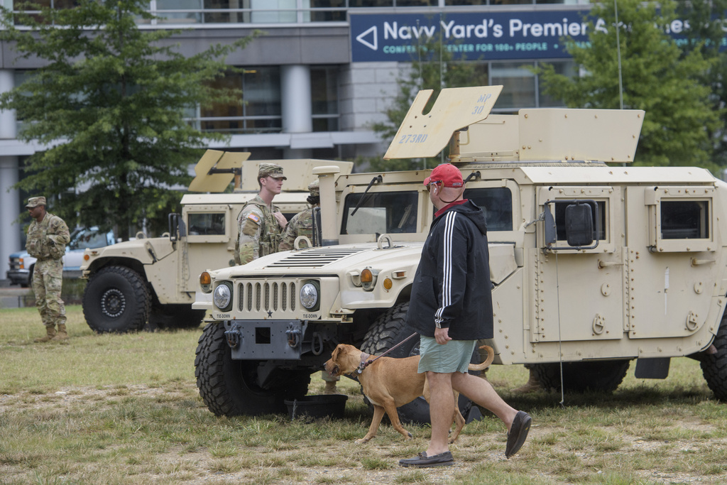 A man walks a dog as District of Columbia National Guardsmen patrol the neighborhood near Nationals Park in Washington, Tuesday, Aug. 19, 2025. (AP Photo/Rod Lamkey, Jr.)