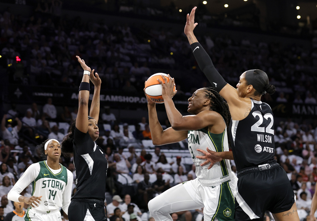 Seattle Storm forward Nneka Ogwumike (3) drives to the basket between Las Vegas Aces forward NaLyssa Smith (3) and center A'ja Wilson (22) during the first half of Game 1 in the first round of the WNBA basketball playoffs Sunday, Sept. 14, 2025, in Las Vegas. Seattle Storm center Dominique Malonga (14) looks on at left. (AP Photo/Steve Marcus)