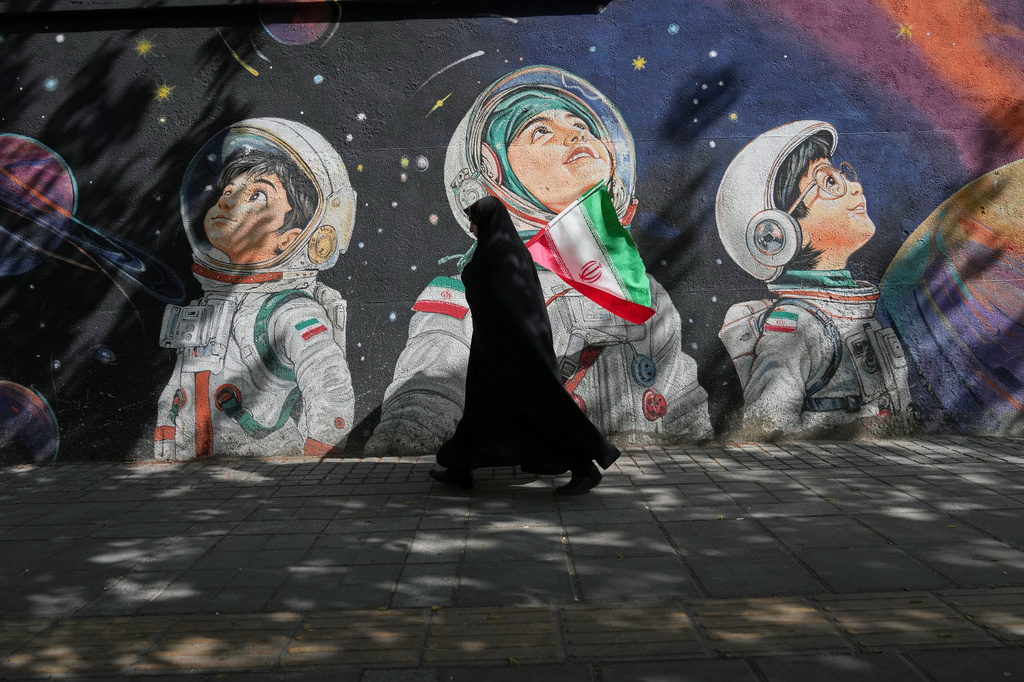 A woman walks past a mural in Tehran, Iran, Wednesday, April 8, 2026. (AP Photo/Francisco Seco)