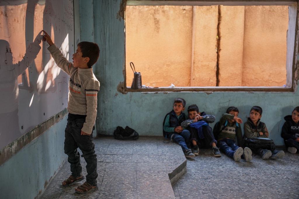 A student points at the whiteboard during a lesson inside a classroom of the Maar Shmarin Primary School in the village of Maar Shmarin, in the Idlib countryside, Syria, Sunday, Oct. 19, 2025. (AP Photo/Ghaith Alsayed)