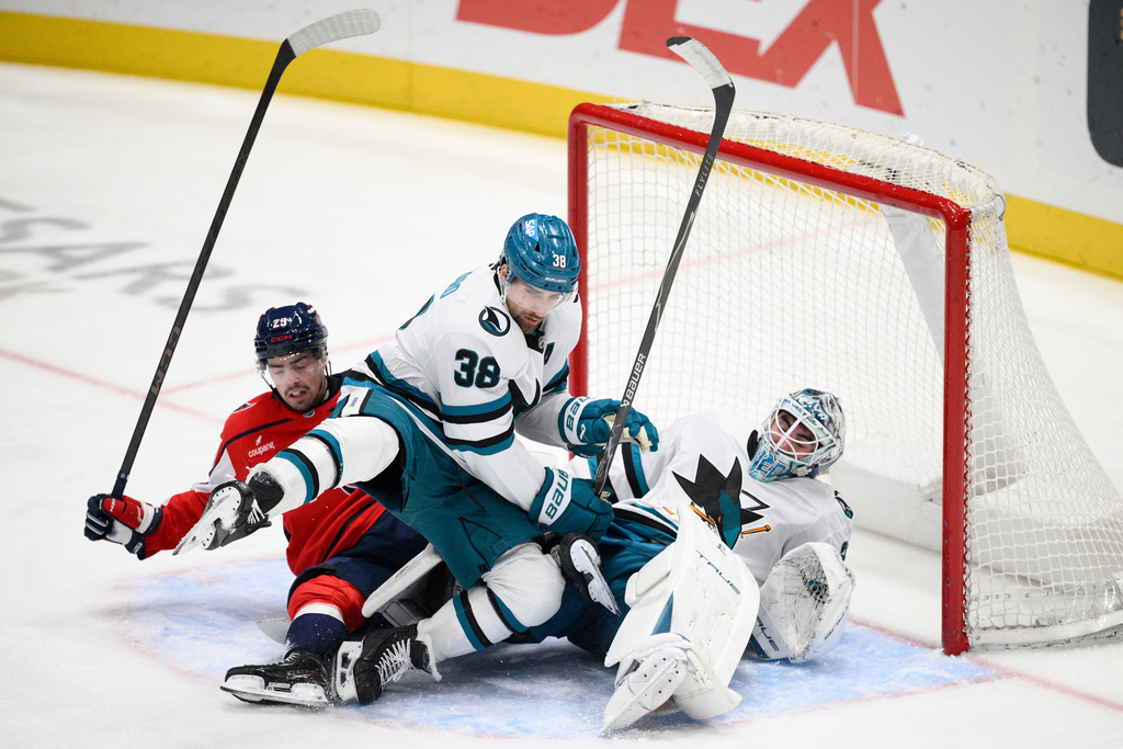 Washington Capitals center Hendrix Lapierre (29) collides with San Jose Sharks defenseman Mario Ferraro (38) and goaltender Alex Nedeljkovic (33) during the third period of an NHL hockey game, Thursday, Jan. 15, 2026, in Washington. (AP Photo/Nick Wass)