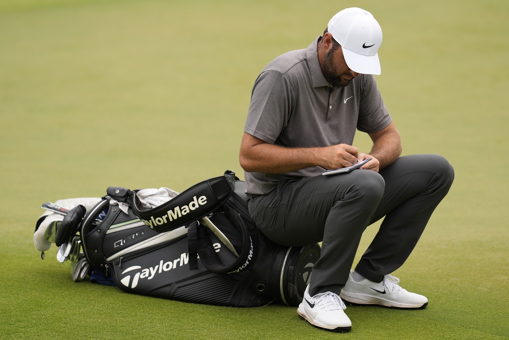 Scottie Scheffler sits on the 18th green during the second round of the Tour Championship golf tournament, Friday, Aug. 22, 2025, in Atlanta. (AP Photo/Mike Stewart)