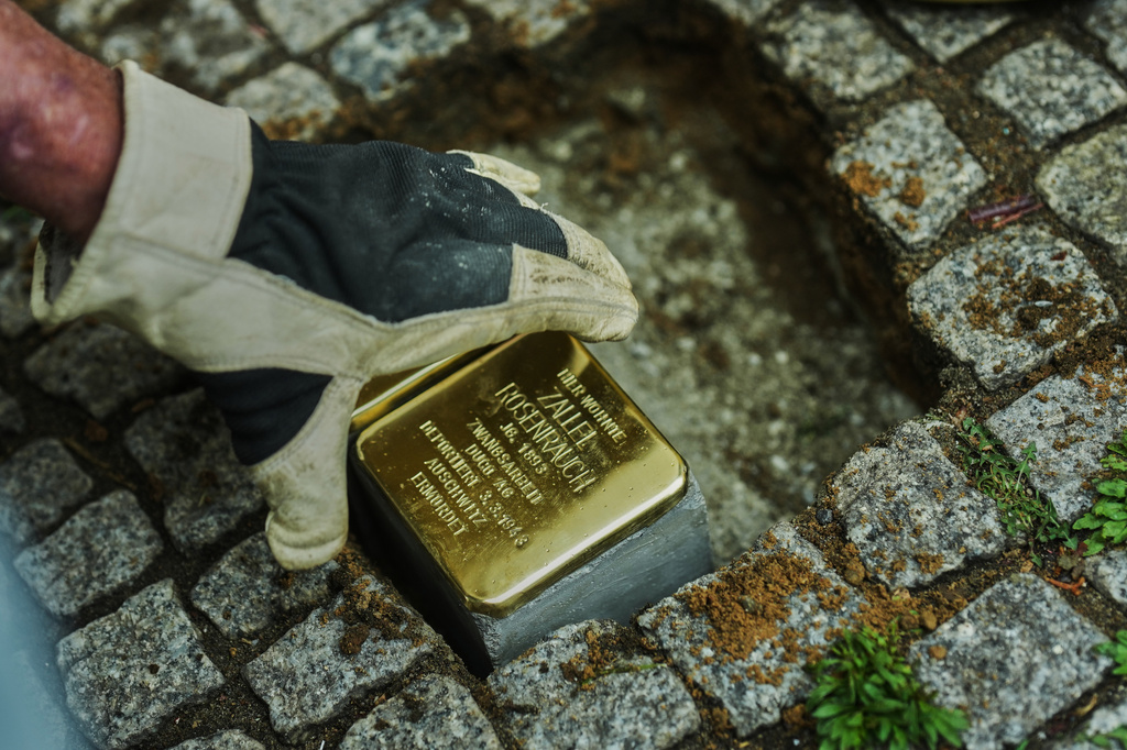 Artist Gunter Demnig places a palm-sized brass Holocaust plaque called "Stolpersteine", or "Stumbling Blocks" with the inscription " Zallel Rosenrauch, born in 1893, lived here; forced labourer at DUCO AG; deported on 3 March 1943; murdered in Auschwitz" front of her former home in Berlin, Germany, Wednesday, May 6, 2026. (AP Photo/Markus Schreiber)