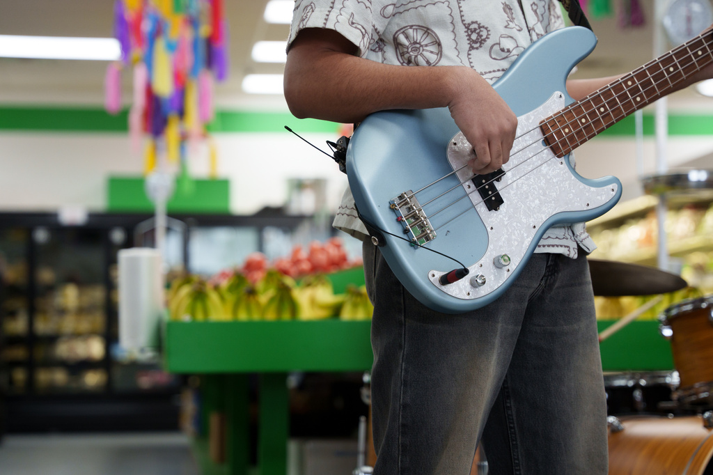 A guitarist performs in the produce section of Fiesta Fresh Market in New Castle, Del., on Sunday, April 26, 2026. (AP Photo/Mingson Lau)
