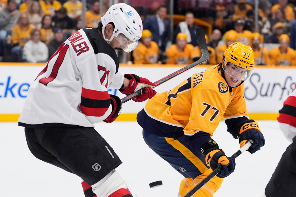 New Jersey Devils defenseman Jonas Siegenthaler (71) and Nashville Predators right wing Luke Evangelista (77) battle for a loose puck during the second period of an NHL hockey game Thursday, March 26, 2026, in Nashville, Tenn. (AP Photo/George Walker IV)