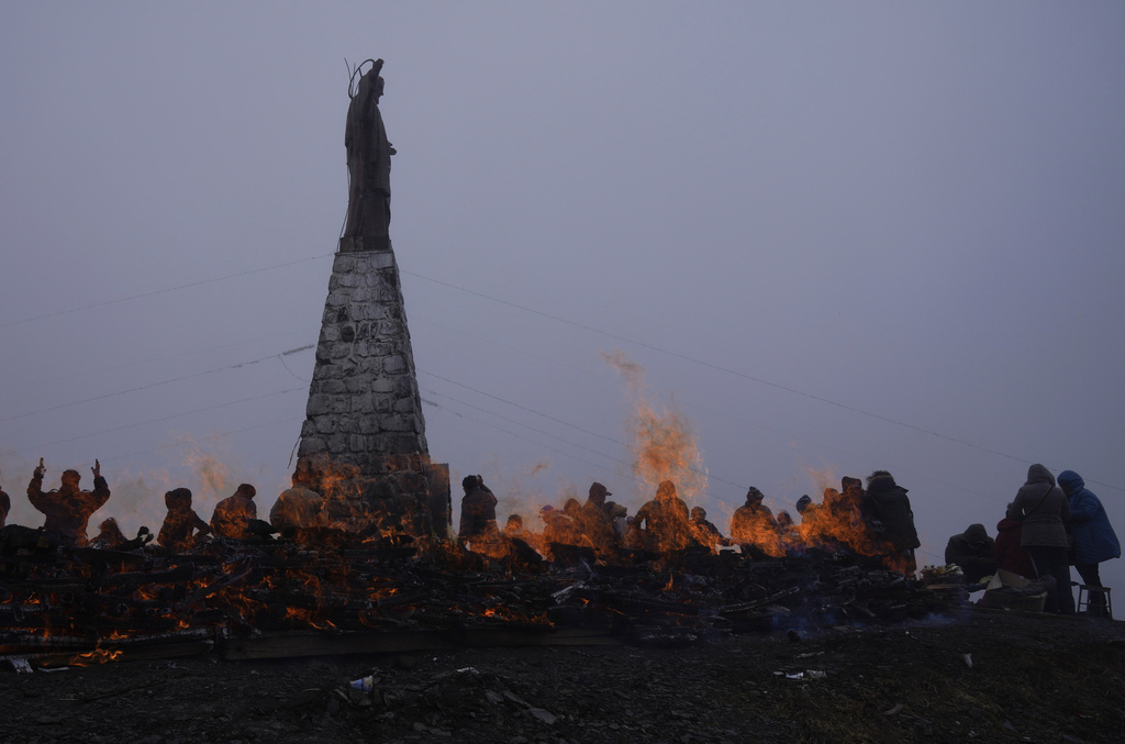 FILE - People burn offerings that include coca leaves in honor of "Pachamama," or Mother Earth, on La Cumbre, a mountain considered sacred where a statue of Jesus Christ stands on the outskirts of La Paz, Bolivia, Aug. 1, 2021. (AP Photo/Juan Karita, File)