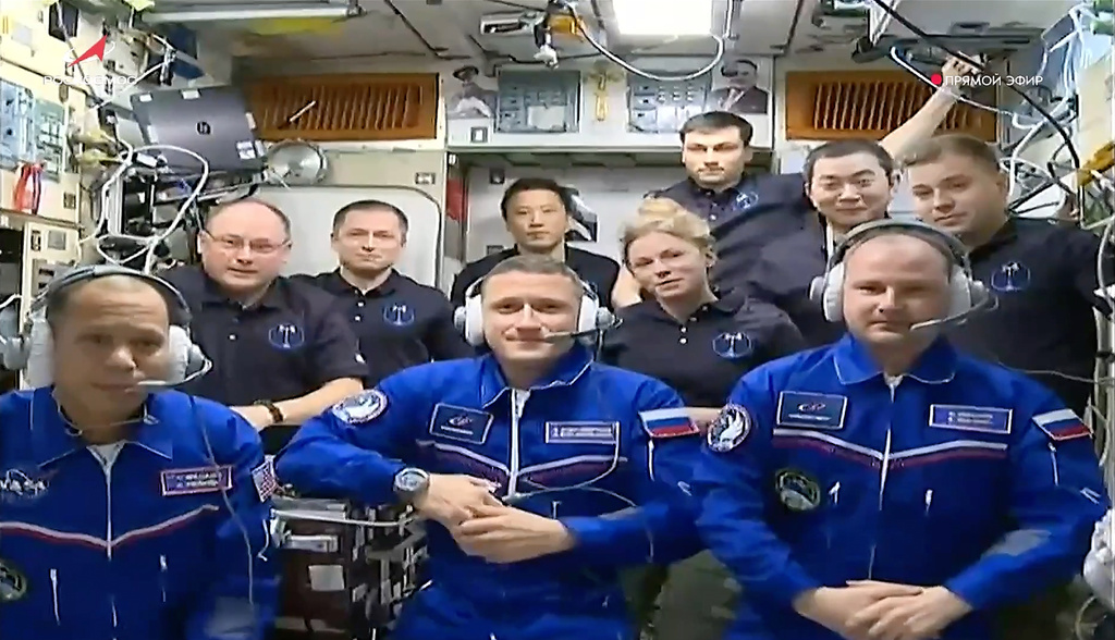 In this image, taken from video footage released by the Roscosmos Space Agency, newly arrived to the International Space Station, wearing blue suits, NASA astronaut Chris Williams, left, Roscosmos cosmonauts Sergey Kud-Sverchkov, center, and Sergey Mikaev pose among other participants of expedition to the International Space Station, after docking the Soyuz MS-28 spaceship to the station on Thursday, Nov. 27, 2025. (Roscosmos Space Agency via AP)