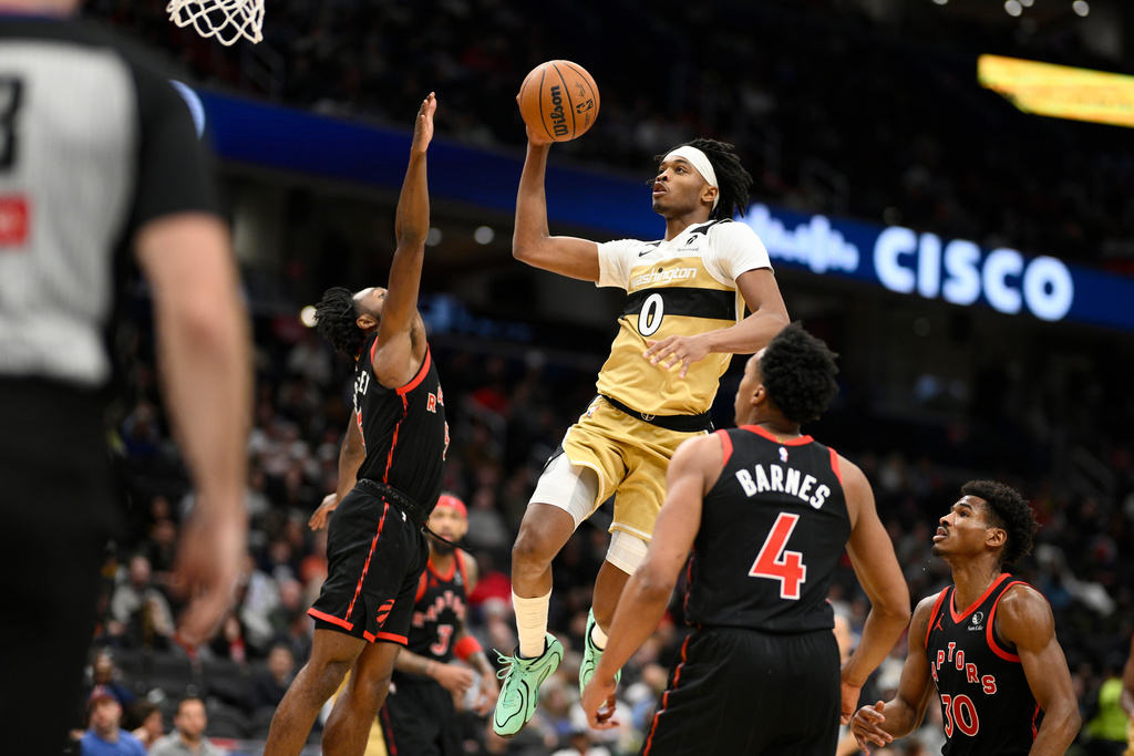 Washington Wizards guard Bilal Coulibaly (0) goes to the basket against Toronto Raptors forward Scottie Barnes (4), guard Ochai Agbaji (30) and guard Immanuel Quickley, left, during the second half of an NBA basketball game, Friday, Dec. 26, 2025, in Washington. (AP Photo/Nick Wass)